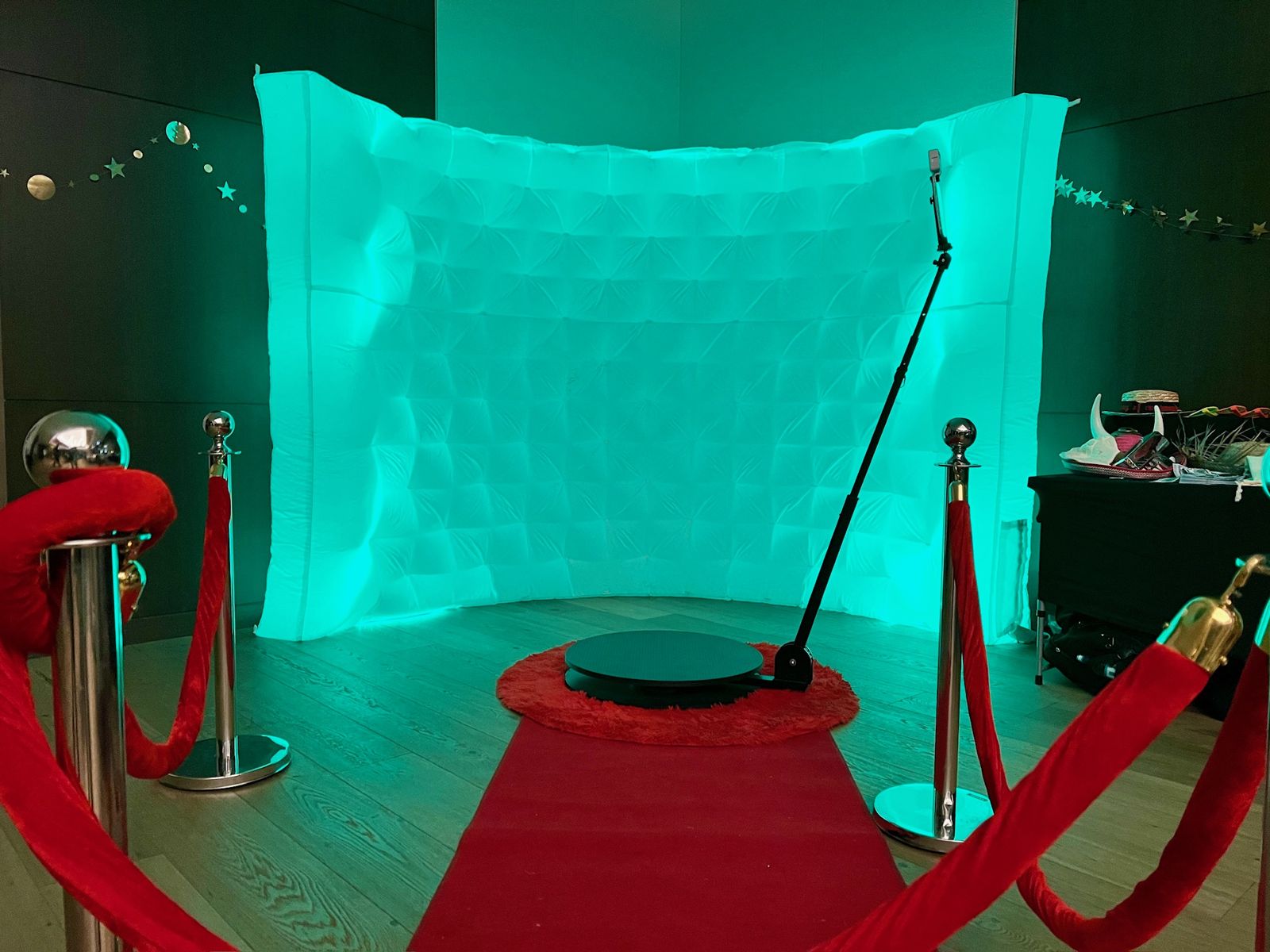 360 photo booth with teal LED backdrop, red carpet and velvet ropes